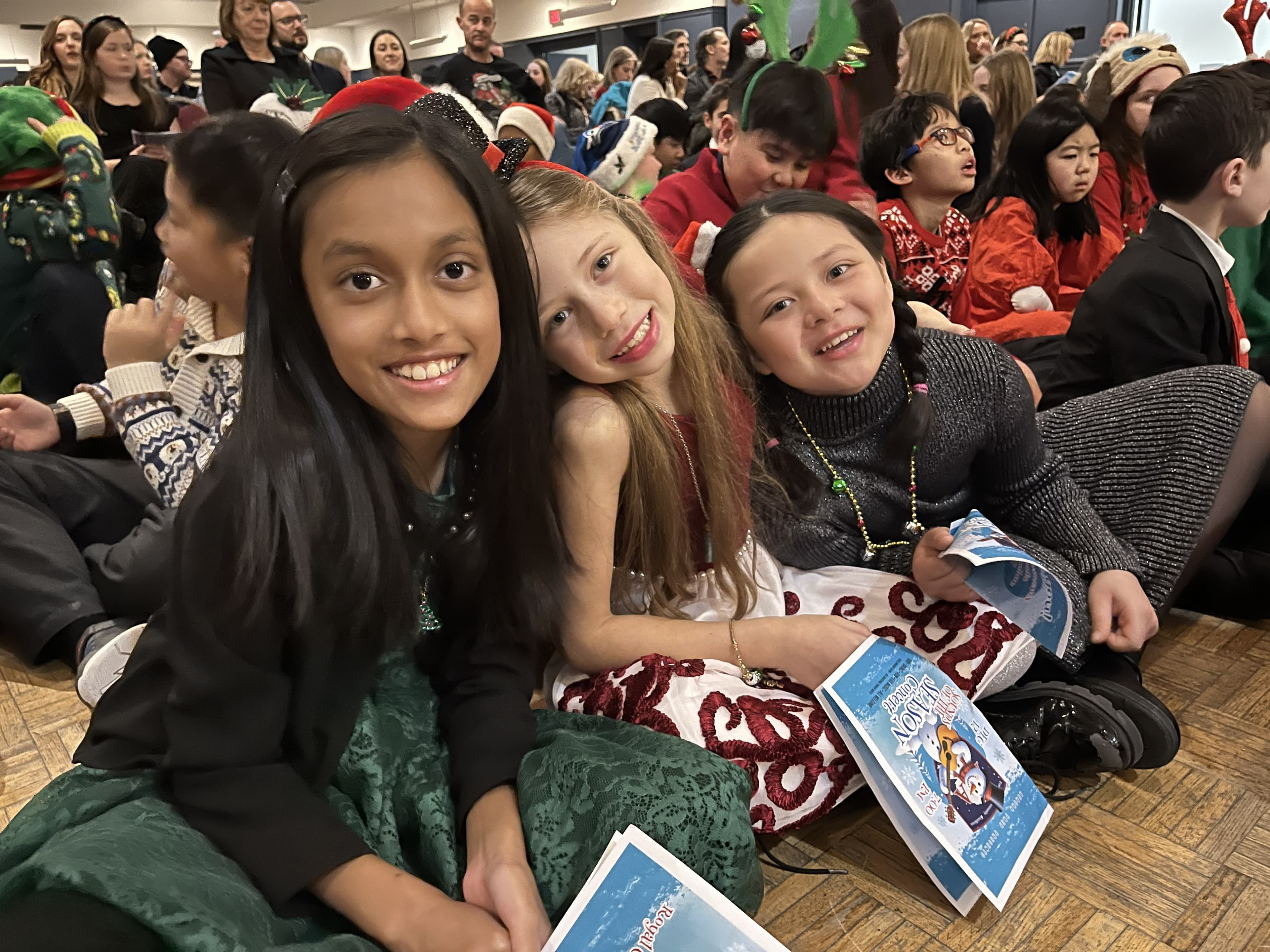Three girls at a Christmas concert in festive dresses